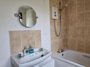 a bathroom with a sink and a tub and a mirror at Widgeon Cottage - Uk33873 in Cote