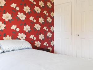 a bedroom with a red wall with white flowers at Widgeon Cottage - Uk33873 in Cote