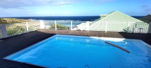 a swimming pool on a deck with the ocean in the background at DV REAL PHILOXENIA Villa in Oyster Pond