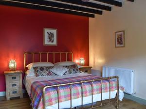a bedroom with a bed with a red wall at The Well House in Starbotton