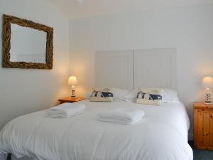 a white bed with two pillows and a mirror at Shore Cottage - Uk12524 in Garlieston