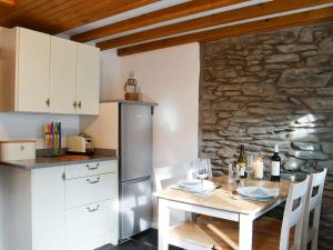 a kitchen with a table and a stone wall at Noddfa Cottage in Llanfair Talhaiarn