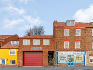 a brick building with red garage doors on a street at Sayers Yard in Whitby