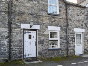 a stone building with a white door and two windows at Noddfa Cottage in Llanfair Talhaiarn