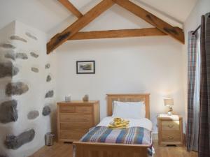 Schlafzimmer mit einem Bett mit einem Kopfteil aus Holz und einer Holzkommode in der Unterkunft Stabal Eithinog in Pen-y-groes