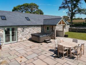 een patio met een barbecue en een tafel en stoelen bij Stabal Eithinog in Pen-y-groes