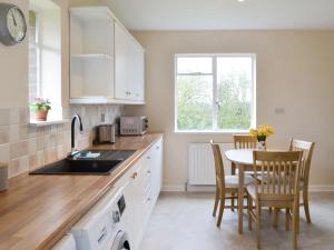 a kitchen with a sink and a table with chairs at North Farm Bungalow in Horsley