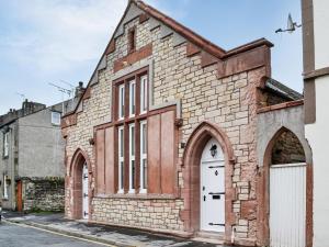 an old brick building with white doors on a street at Chapel Mouse Cottage in Cockermouth