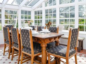 a conservatory dining room with a wooden table and chairs at The Garden Rooms in Montrose