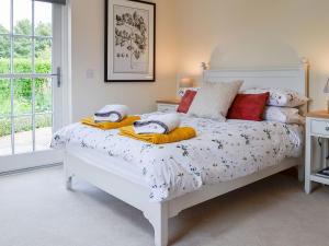 The Garden Rooms في مونتروز: غرفة نوم بسرير ابيض مع بطانيات ومخدات صفراء