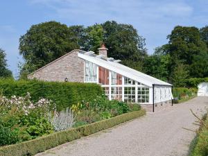 a greenhouse in front of a brick house at The Garden Rooms in Montrose