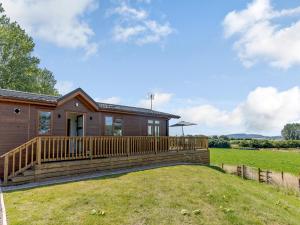 a house with a large deck in a field at Nanny Goat Lodge in Crossway Green