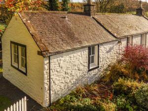 mały kamienny budynek z dachem w obiekcie Bridge Cottage w mieście Lockerbie