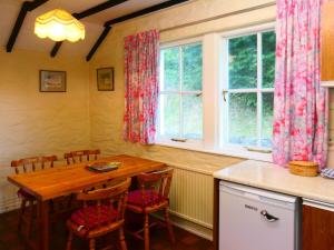 kuchnia z drewnianym stołem i krzesłami obok okna w obiekcie Bridge Cottage w mieście Lockerbie