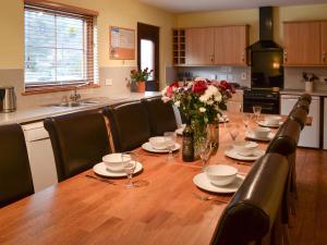 una cocina con una mesa de madera con platos y flores. en Woodland Lodge, en Boat of Garten