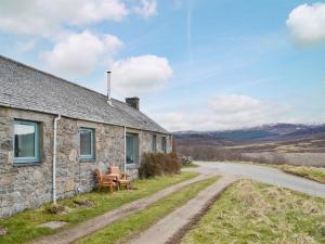 a stone house with a bench next to a road at The Grain Store in Aberarder