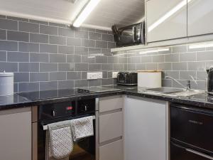 a kitchen with stainless steel appliances and blue tiles at Cuillin View Apartment - Uk12529 in Arisaig