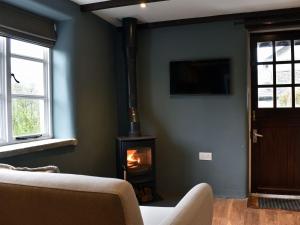 a living room with a wood stove in the corner at Strawberry Cottage in Combe Martin
