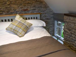 a bed with a pillow and a stone wall at Strawberry Cottage in Combe Martin