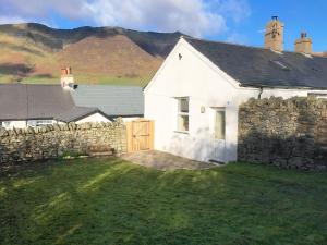 a white house with a stone wall at Katellen Cottage in Threlkeld