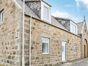an old stone house with white windows on a street at Forvie View in Collieston