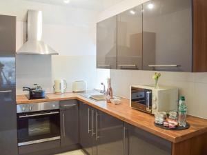 a kitchen with a wooden counter top with a microwave at The Cottage in Girvan