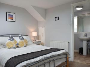 a bedroom with a white bed with pillows and a sink at Windy Dales Cottage in Skipton