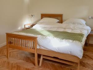 Un dormitorio con una gran cama de madera con sábanas blancas. en Dowie House Steading, en Cheswick