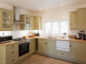 a kitchen with white cabinets and a stove top oven at The Gatehouse Cottage in Wells