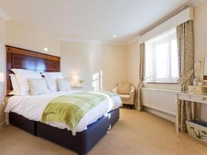 a bedroom with a large bed and a chair at The Gatehouse Cottage in Wells