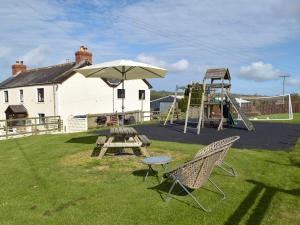 a playground with a picnic table and a swing set at Pengelli Cottage in Eglwyswrw