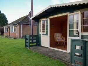 una casa verde con una puerta y una silla en una cubierta en Kinverley, en Evenjobb