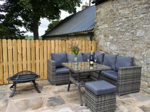 a patio with wicker chairs and a table and a fence at Harsondale Bothy in Langley