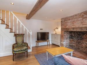 a living room with a brick fireplace and a tv at Clematis Cottage in Thorpe Market