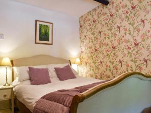 a bedroom with a bed with a floral wallpaper at Uk34351 - Squirrel Cottage in Betws-y-coed
