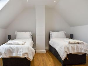 two beds in a room with white walls and wood floors at Fallow Cottage - Uk33488 in Hadleigh