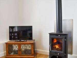 a living room with a stove and a tv at Fallow Cottage - Uk33488 in Hadleigh