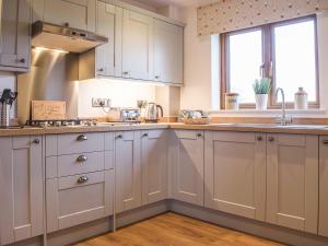 a kitchen with white cabinets and a sink at The Larches in Hopton Cangeford