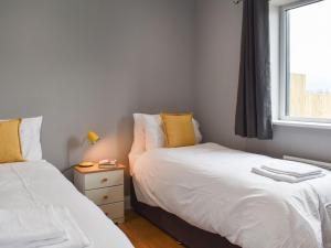 2 Betten in einem kleinen Zimmer mit Fenster in der Unterkunft Badger Lodge - Uk30603 in Pidley
