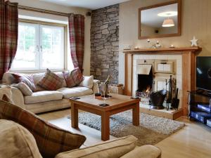 sala de estar con sofá y chimenea en Baldowrie Farm Cottage en Ardler