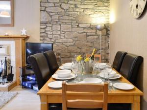 mesa de comedor con sillas y pared de piedra en Baldowrie Farm Cottage en Ardler