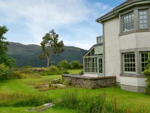 a house with a green yard and mountains in the background at Stronafian House in Feorlean