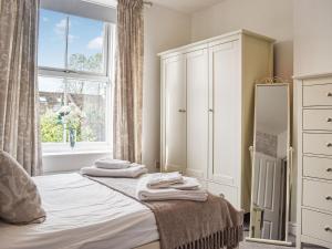a bedroom with a bed with a dresser and a window at Flat 3 Avon Villa in Bradford on Avon