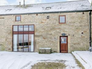 un edificio de ladrillo con una puerta en la nieve en Woodlands Clough - Uk32387, en Dunford Bridge