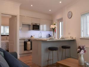a kitchen and living room with a counter and stools at Kingsley Cottage in Darenth