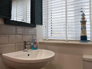 a bathroom with a sink and a lighthouse in the window at Kingsley Cottage in Darenth