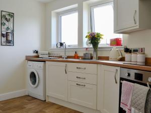 een keuken met een wastafel en een wasmachine bij Blueacres in Skirling