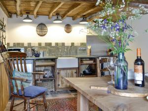 a kitchen with a wooden table with a vase of flowers at Springlea Cottage in Dean