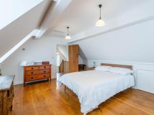 a bedroom with a white bed and a wooden dresser at Jasmine Cottage in Hilgay