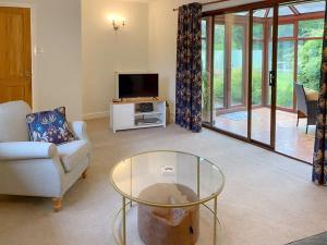 a living room with a tv and a glass table at Rose Cottage in Blakemere